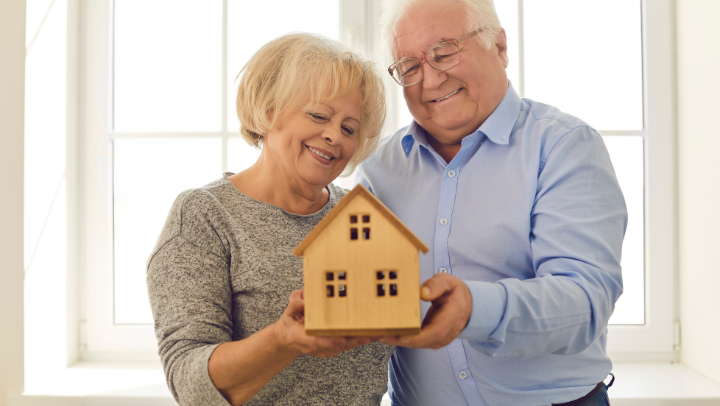 elderly couple holding a house