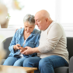 elderly couple sitting on couch looking a blood sugar levels