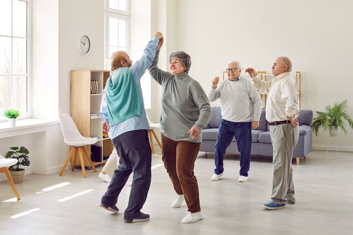Group of older adults dancing in a senior living community
