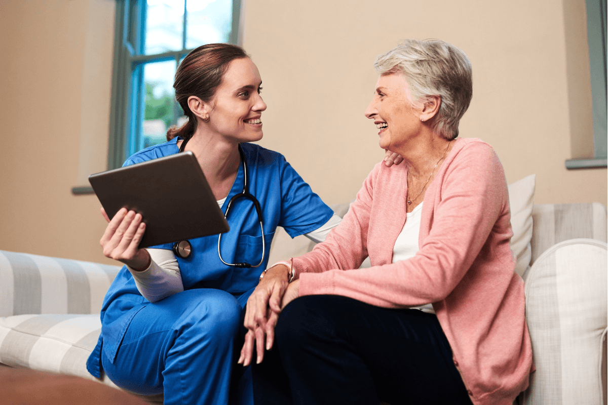 Senior woman, caregiver and tablet on sofa at house for medical schedule, healthcare and wellness report.